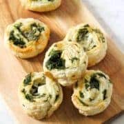 spinach and feta pinwheels on a wooden serving board.
