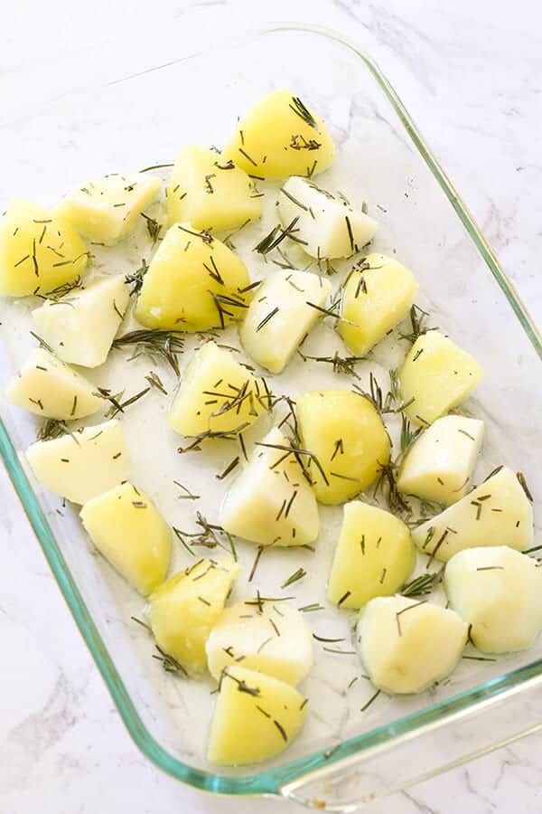 Potato pieces in a glass baking tray ready for the oven. 