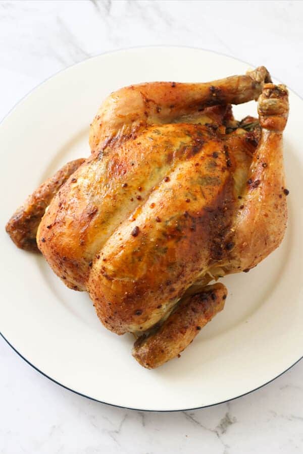 Whole roast chicken on a white plate.