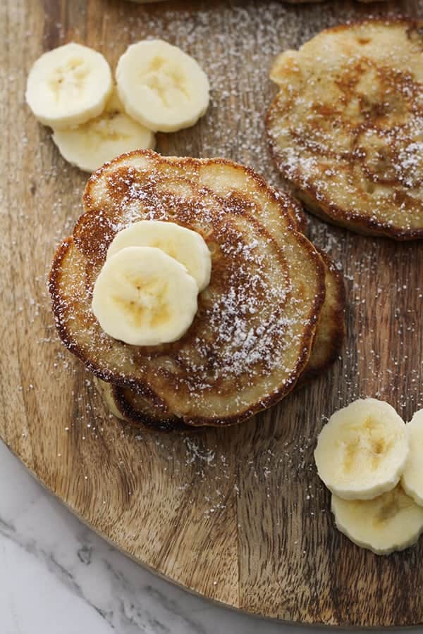 pikelets stacked on top of each other on a wooden board.