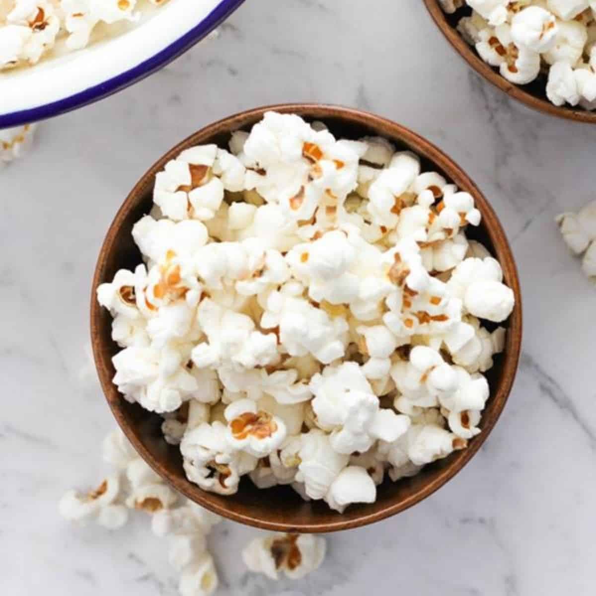 popcorn in a wooden bowl with text overlay "how to make stovetop popcorn".
