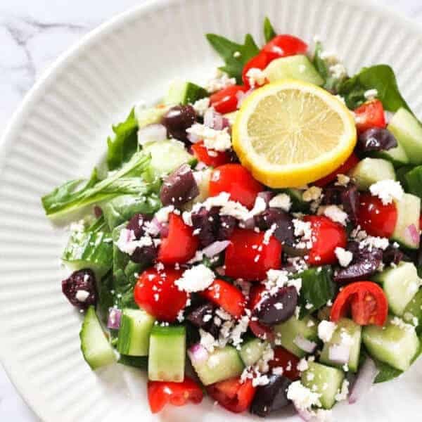 close up image of greek salad topped with lemon slice