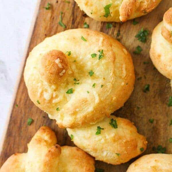 garlic knots on a wooden serving board.