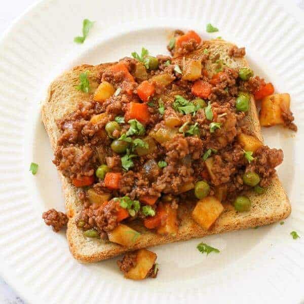 Savoury mince on top of a piece of toast on a white plate.