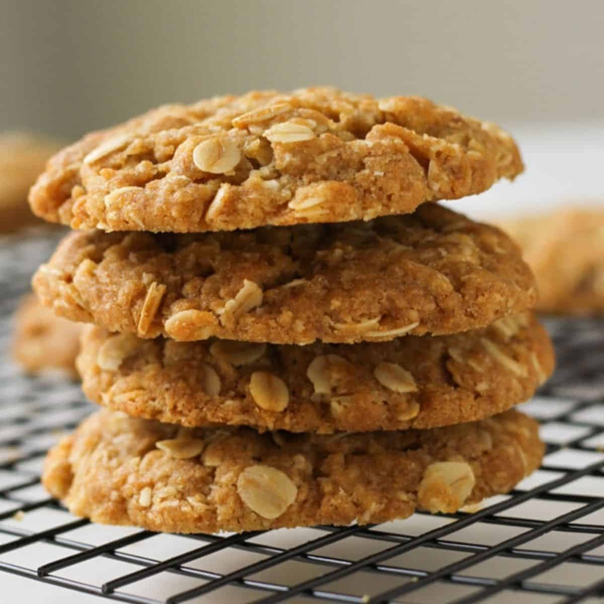 Chewy Anzac biscuits stacked on top of each other on a wire rack.