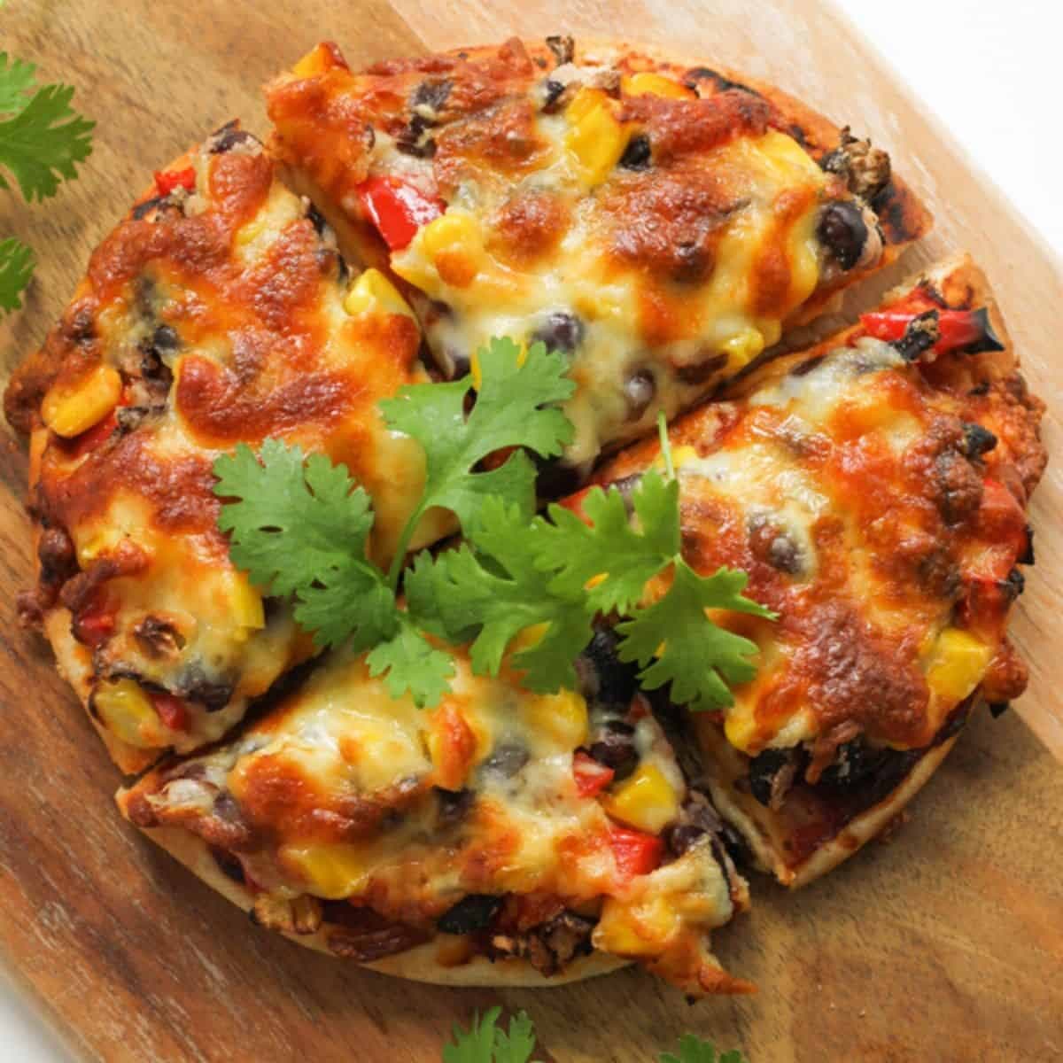 pizza cut into quarters on a wooden board.