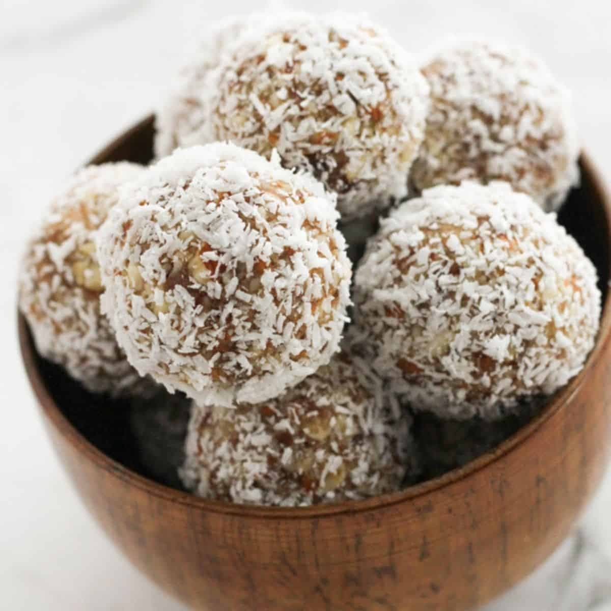 date coconut energy balls in a wooden bowl.