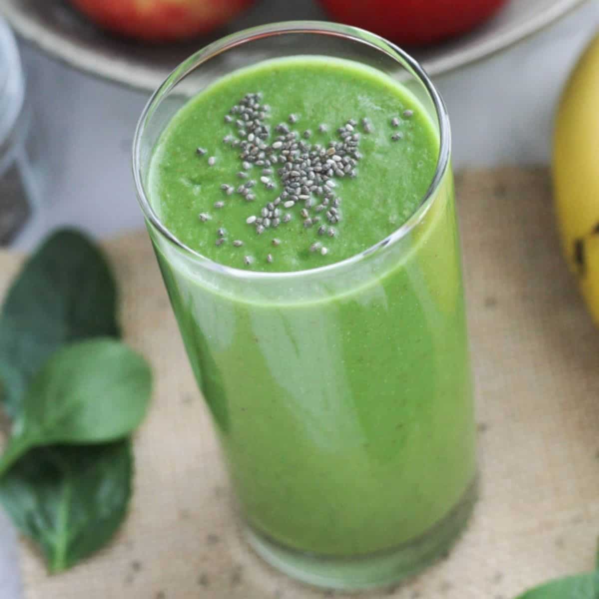 green smoothie in a tall glass topped with chia seeds.
