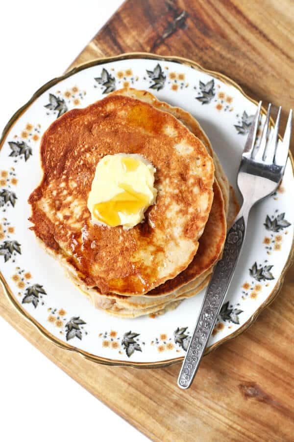 healthy banana pancakes on a patterned plate with a square of butter and maple syrup drizzled on top