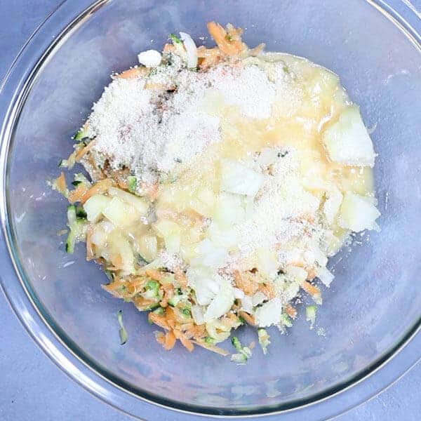 carrot and zucchini fritters ingredients in a glass bowl