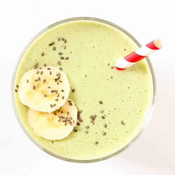 green smoothie in a glass topped with chia seeds and banana slices