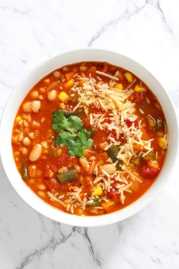 vegetable barley soup topped with parmesan cheese and coriander