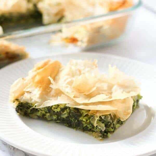 a slice of spanakopita on a white plate