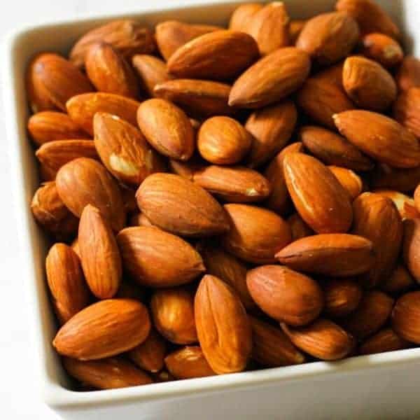 Roasted almonds in a white square serving bowl.