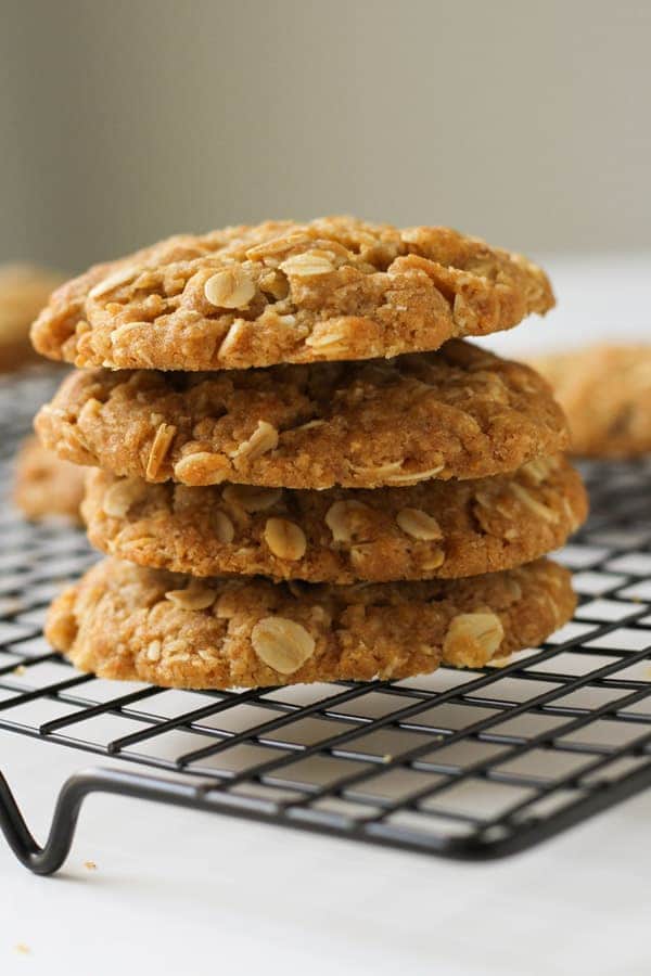 anzac biscuits stacked on top of each other on a wire rack.