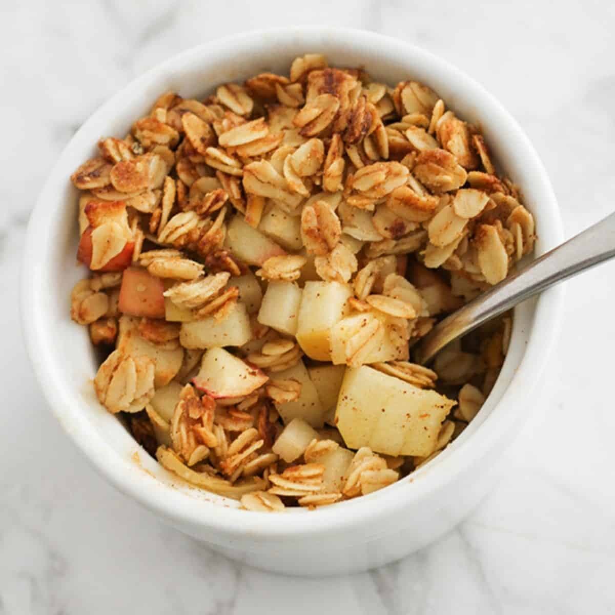 apple crisp in a white ramekin with a spoon.