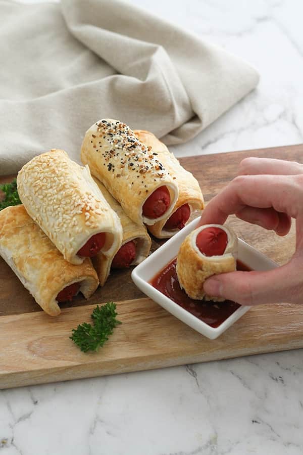 puffy dogs stacked on a wooden serving board.