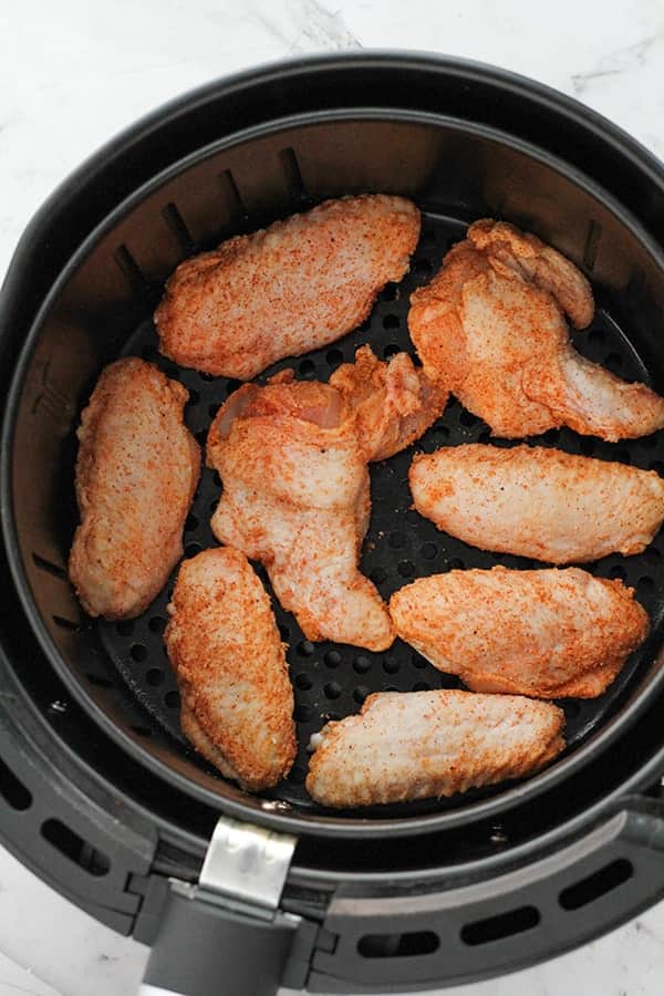 crispy chicken wings in an air fryer basket.