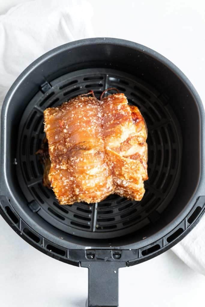 cooked roast pork in an air fryer basket.