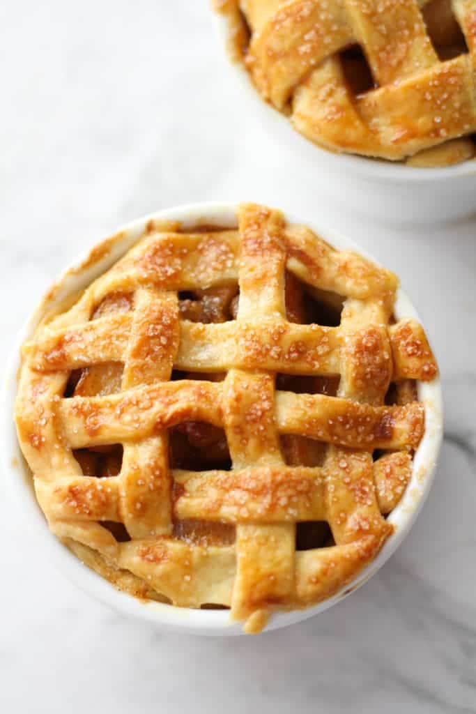 two mini apple pies in white ramekins.