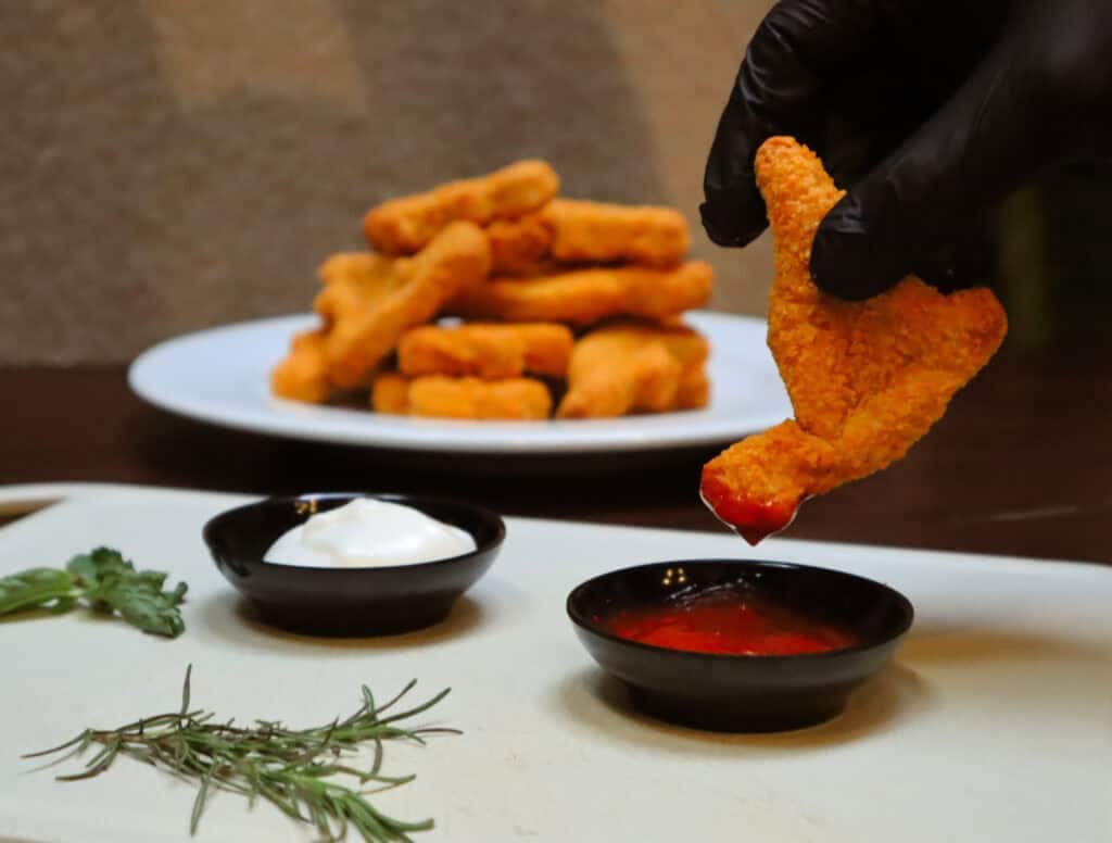 Dino nuggets dipping in hot sauce