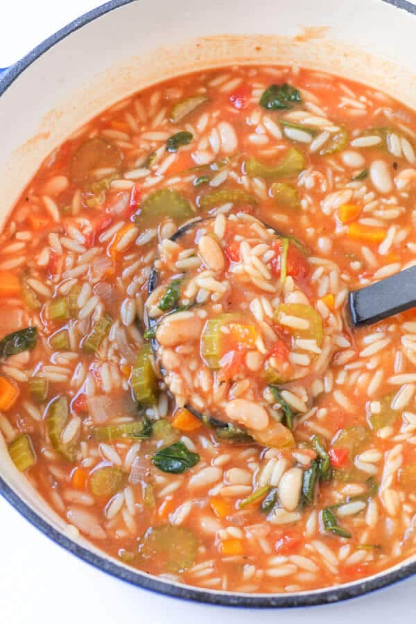 italian vegetable orzo soup in a blue rimmed dutch oven