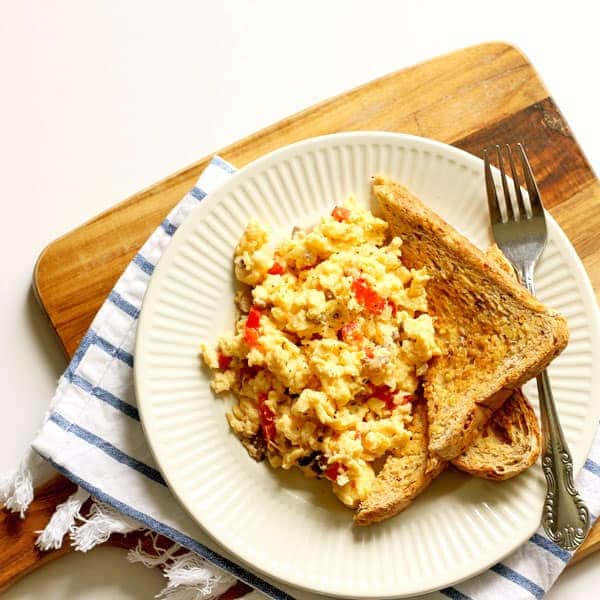 Easy scrambled eggs with veggies and two pieces of toast on a white plate