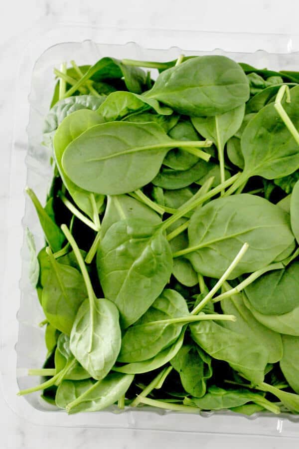 loose spinach leaves in a plastic container
