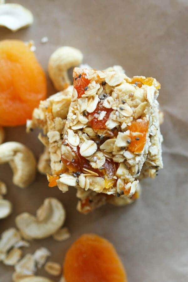 chewy apricot muesli bars stacked on top of each other with cashews and apricots scattered around