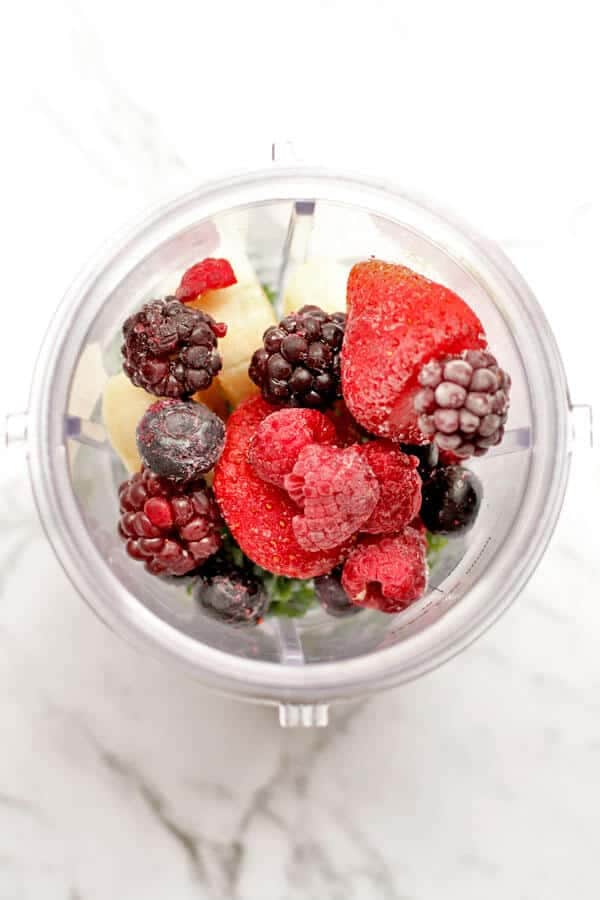 berry green smoothie ingredients in a blender cup
