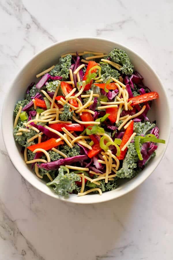 crunchy kale salad with lemon tamari dressing in a white bowl