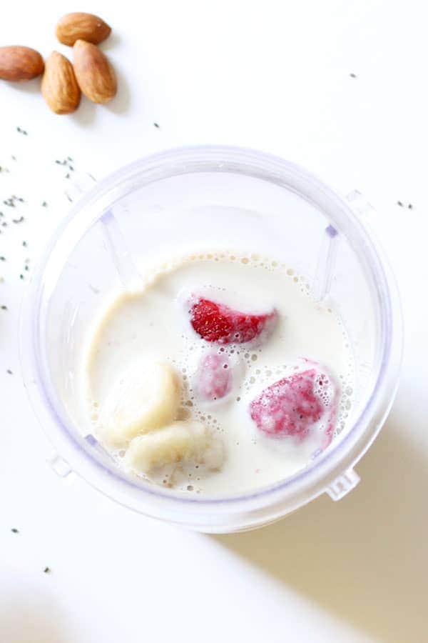 ingredients for strawberry banana smoothie bowl in a blending cup