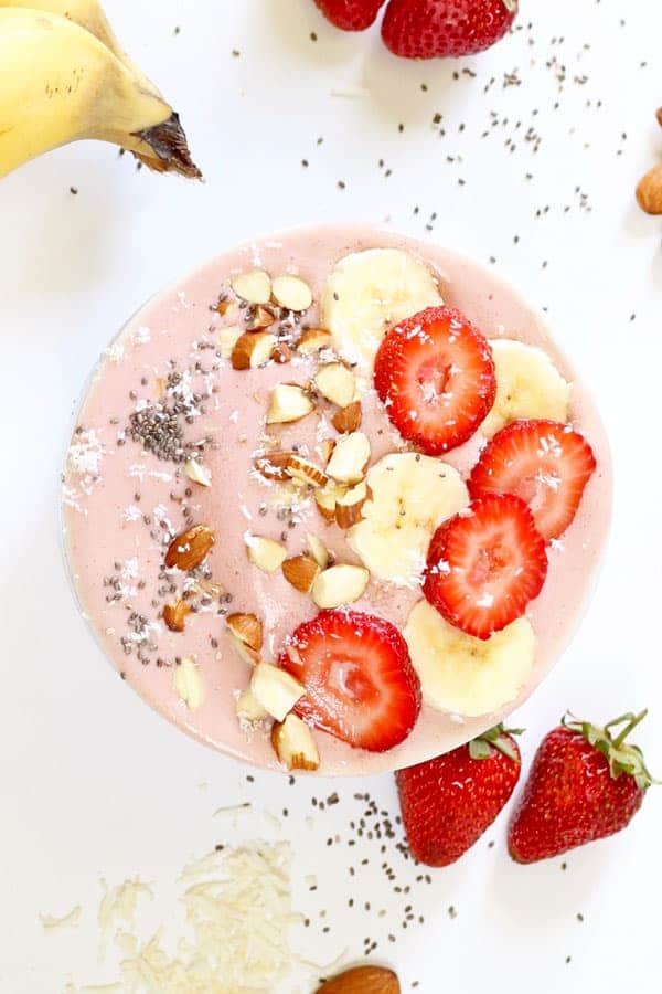 strawberry banana smoothie bowl surrounded by ingredients