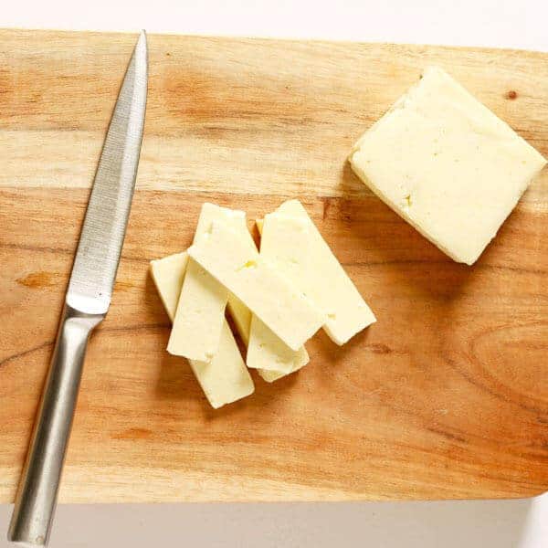 sliced haloumi cheese on a wooden cutting board