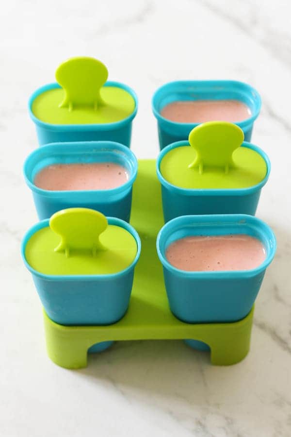 popsicle moulds filled with strawberry banana popsicle mix.