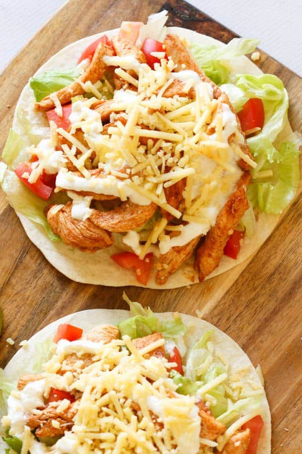 2 chicken tacos on a wooden cutting board