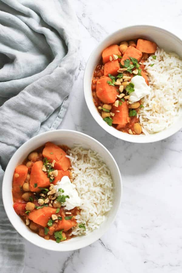 two white bowls of sweet potato, lentil & chickpea curry next to a grey napkin