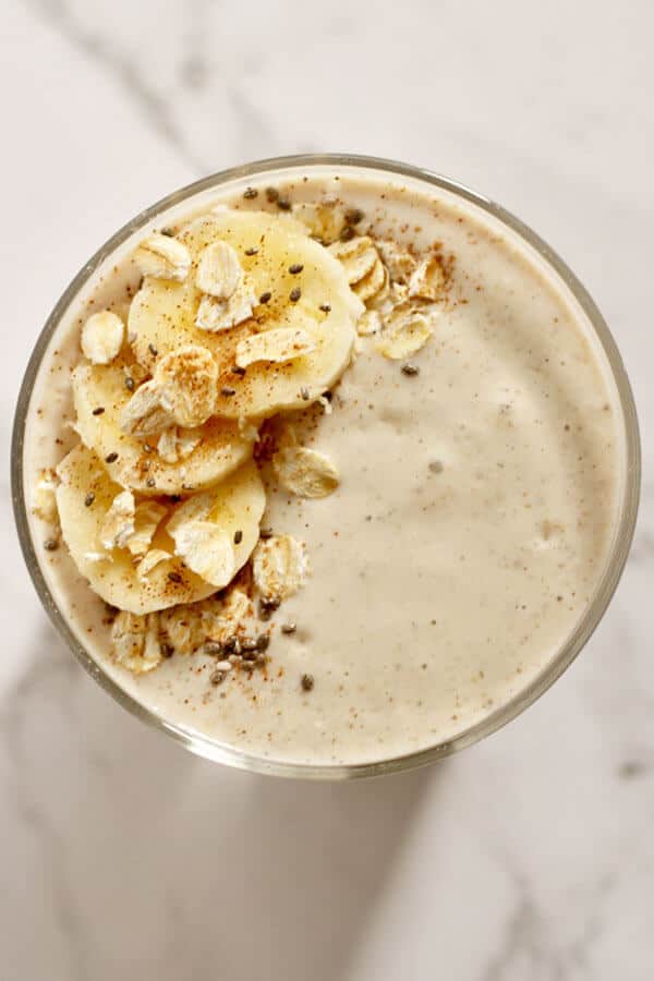 banana oat smoothie from above topped with banana slices, oats, cinnamon and chia seeds