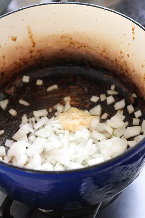 onion and garlic in a blue dutch oven.
