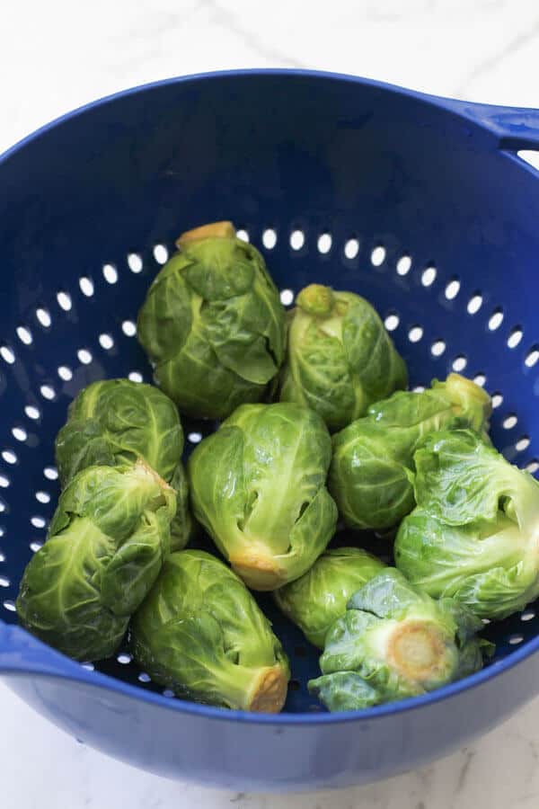 freshly rinsed whole brussels sprouts sitting in a colander 