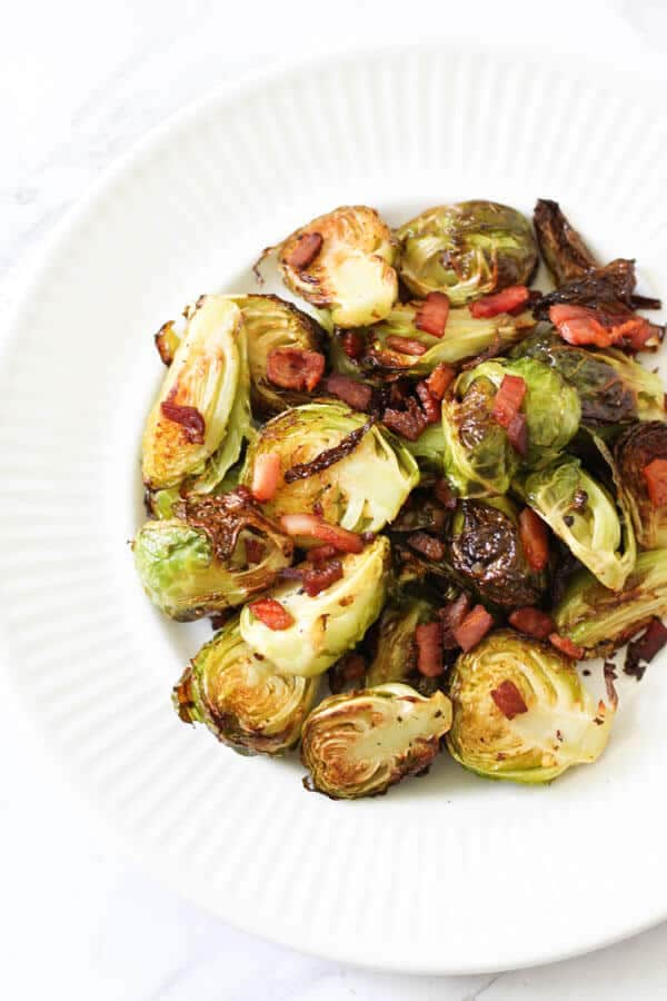 roasted brussels sprouts with bacon on a white plate