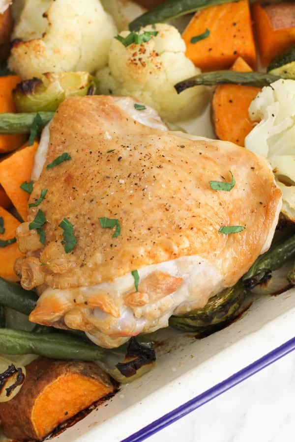 crispy baked chicken thighs on a baking tray with vegetables.