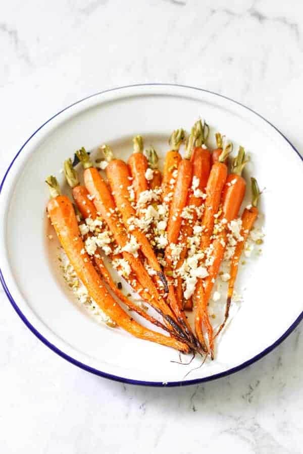 roasted carrots on a white plate with feta and dukkah sprinkled on top 