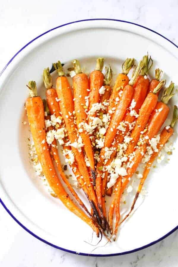 roasted carrots on a white plate with feta and dukkah sprinkled on top 