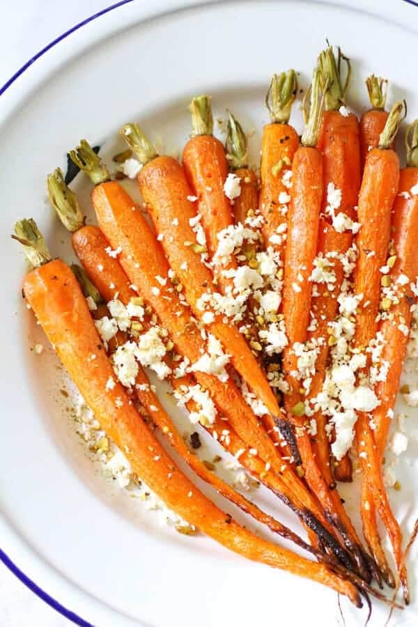 roasted carrots on a white plate with feta and dukkah sprinkled on top 
