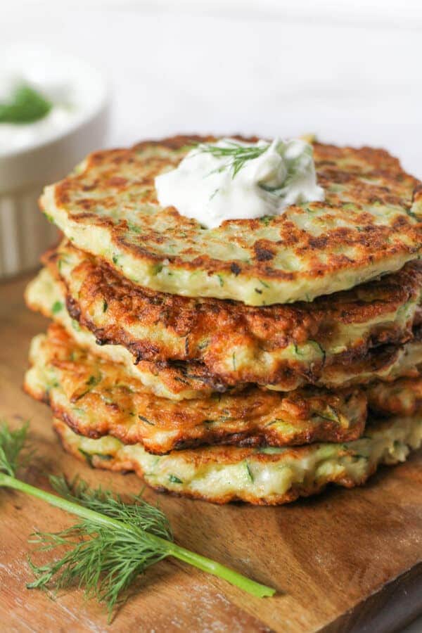 a stack of zucchini fritters Kolokithokeftedes with tzatziki pooled on top