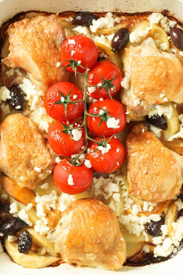 cooked chicken thighs and vegetables in a white tray