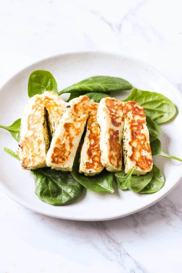 grilled halloumi on a bed of spinach leaves.