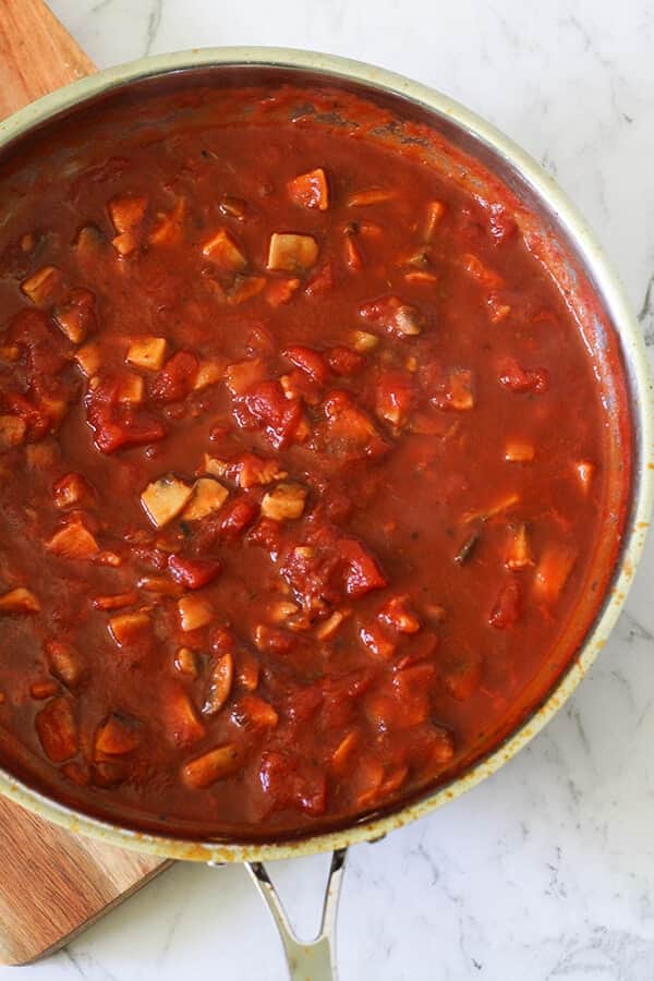 a saucepan filled with a tomato based bacon and mushroom pasta sauce.