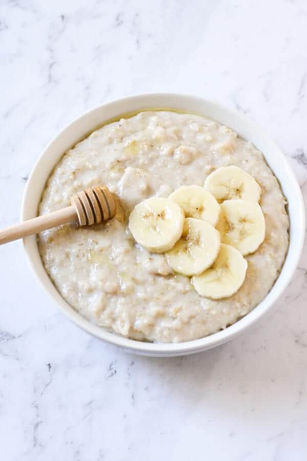 a bowl of oatmeal topped with banana slices and honey.